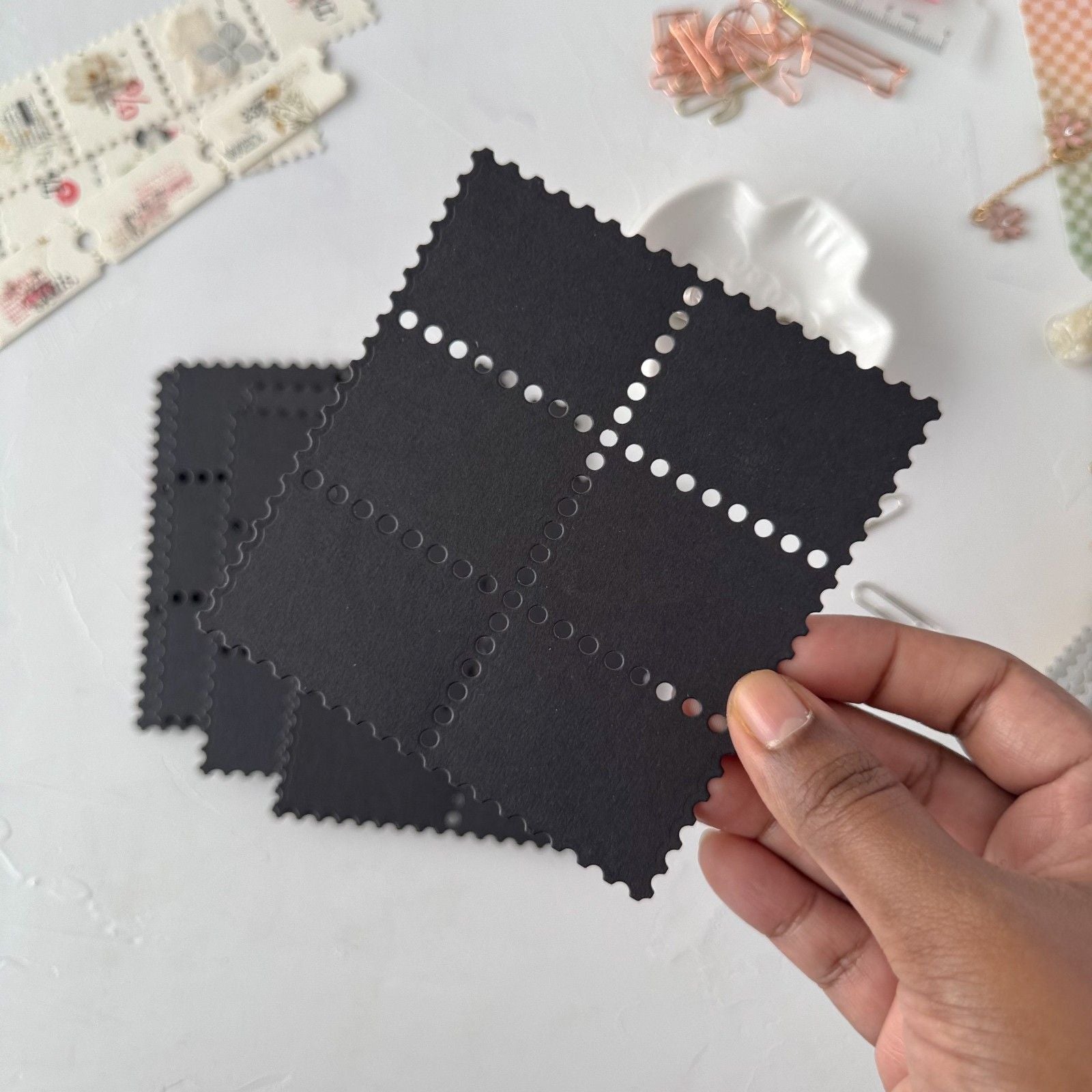 Hand holding a black Stamp Card Vol. 3 ephemera card with more cards on a light backdrop