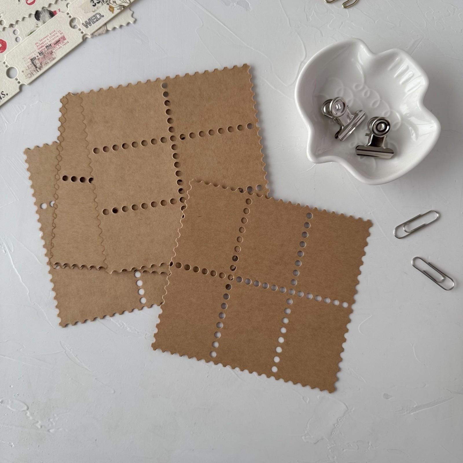 Brown square tiles with holes on a white surface with clips.
