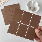Brown textured square tiles with a hand holding one, on a light surface.