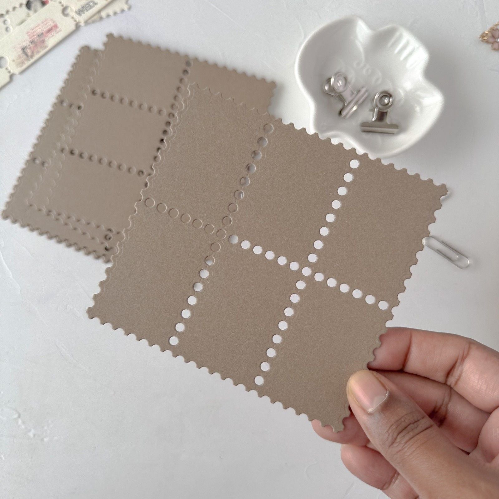 Brown fabric swatch with a grid pattern held by a hand on a white background