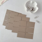 Brown square placemats with perforated edges on a white surface.