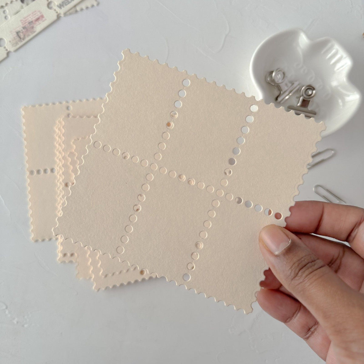Hand holding cream Stamp Card Vol. 3 cards with a star cutout pattern on light grey