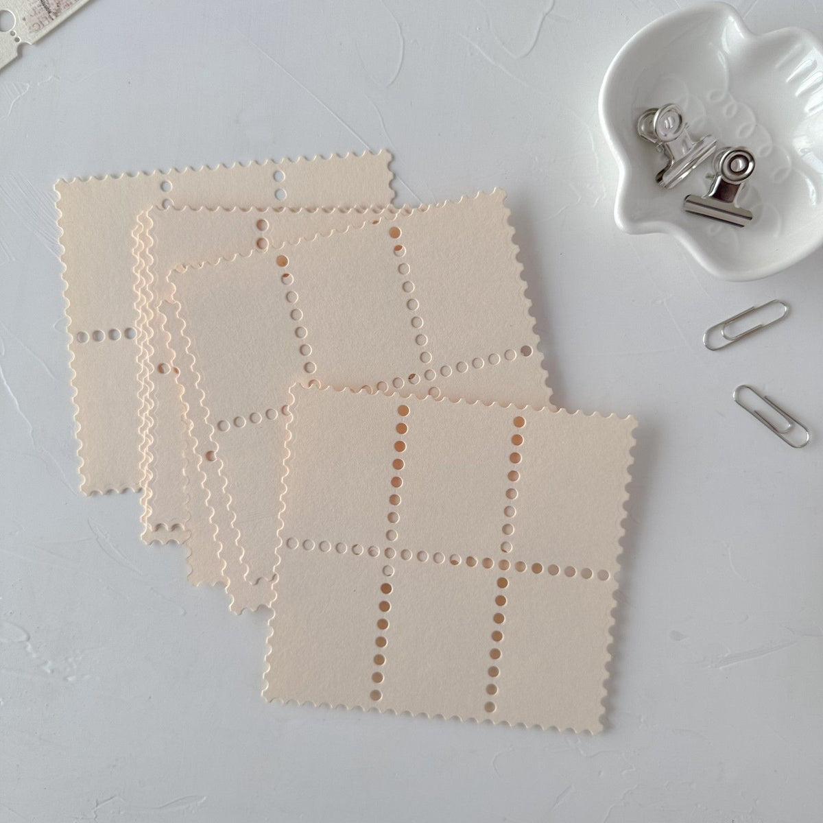Set of cream Stamp Card Vol. 3 square cards with perforated edges on a light grey surface