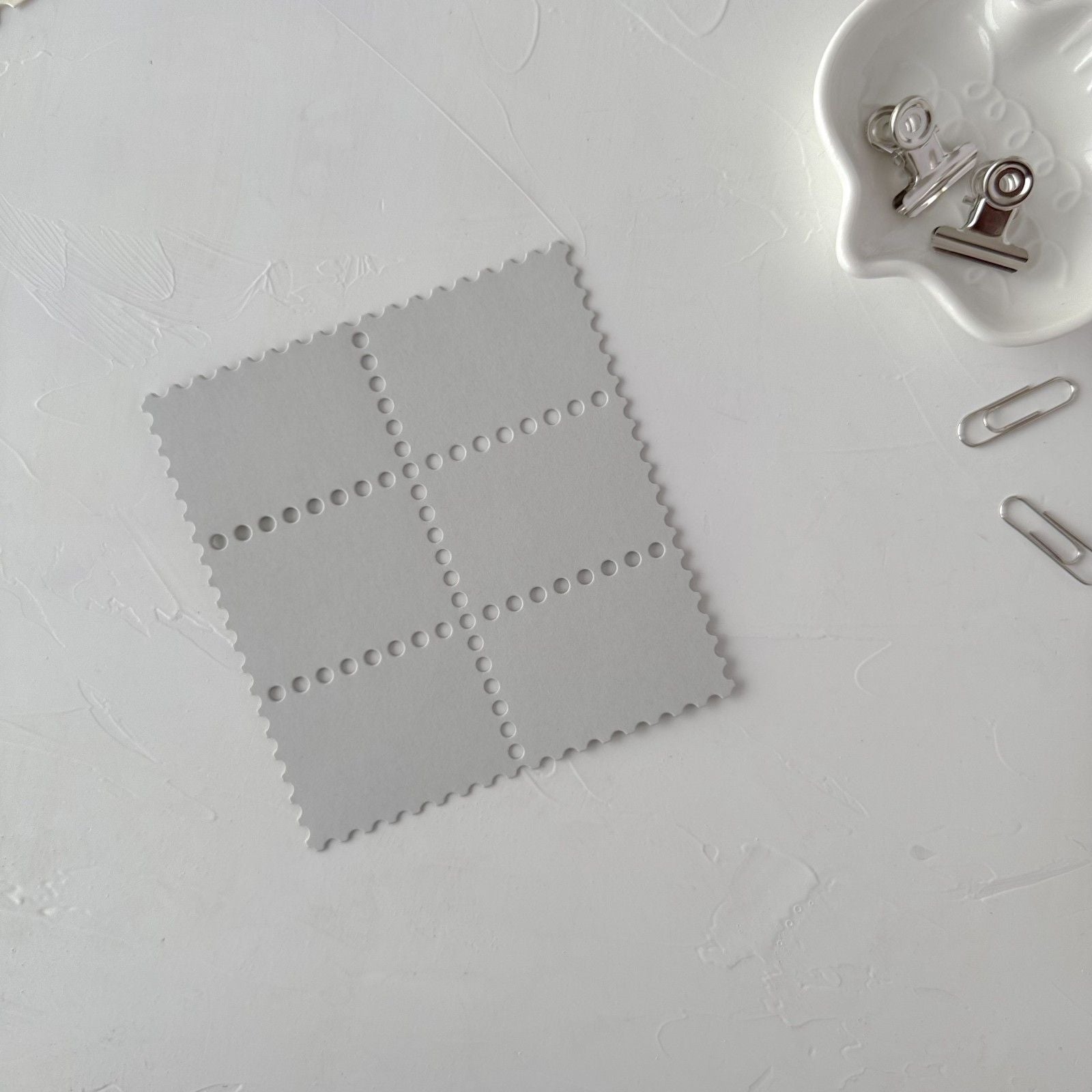 Gray swatch on a white background with a clip and paper clips nearby.