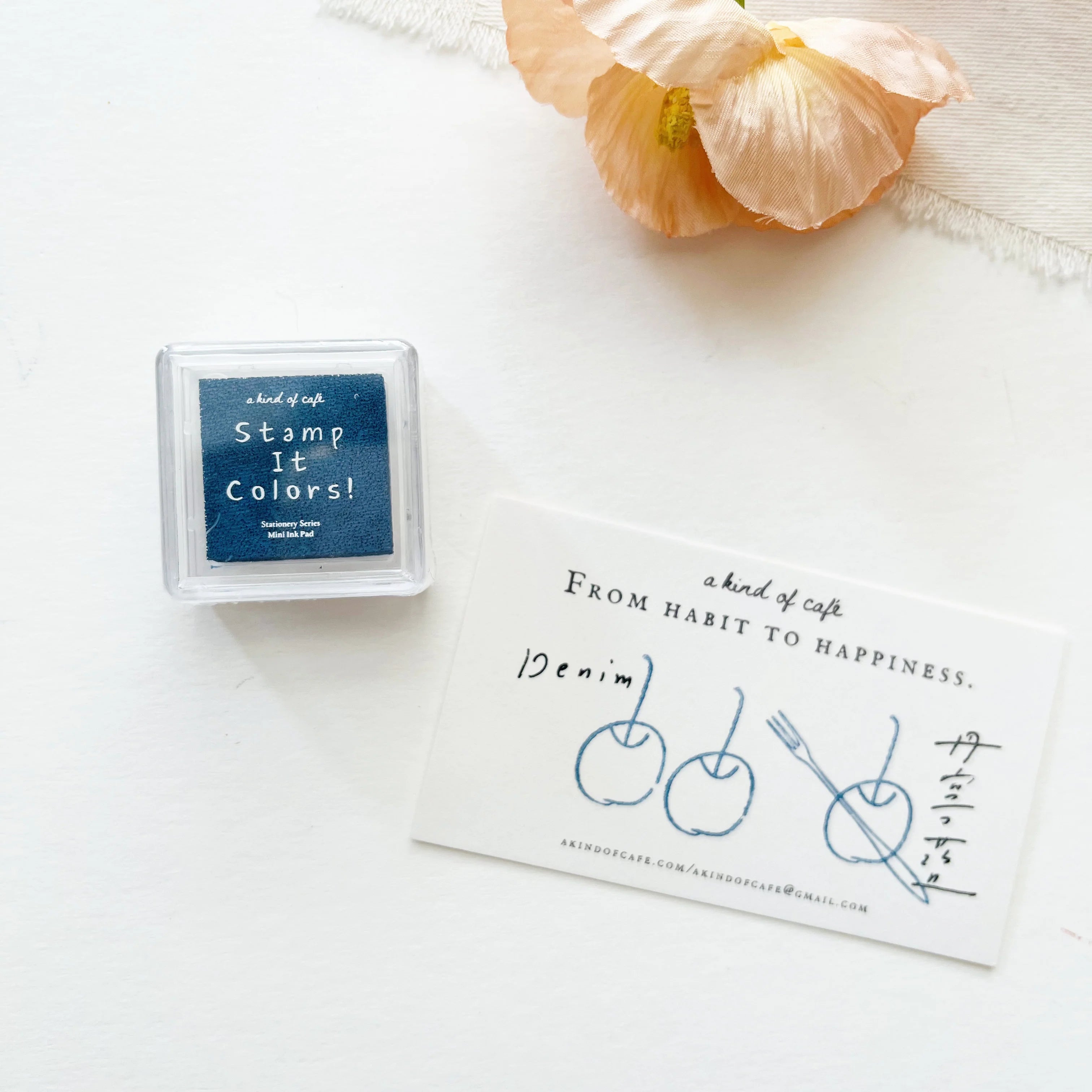 Rectangular stamp pad with 'Stamp It Colors!' text on a white surface with a flower.