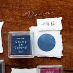 Denim ink pad with a sample color swatch on a wooden surface