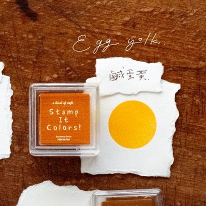 Stamp pad with orange ink and a yellow stamp on a wooden background