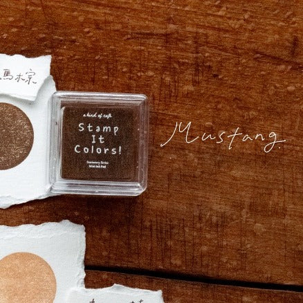 Brown ink pad with 'Stamp It Colors!' text on a wooden surface