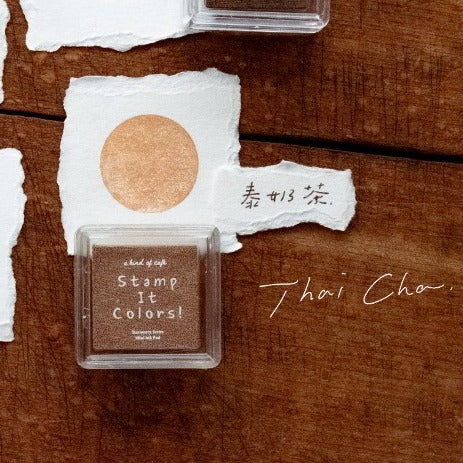 Brown stamp pad with 'Stamp It Colors!' text on a wooden surface