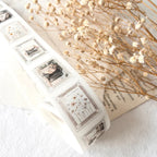Decorative washi tape with vintage-style designs on a textured surface with dried flowers.