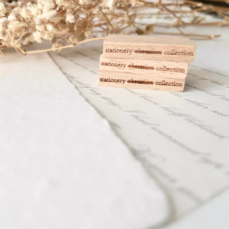 Wooden Stationery Obsession Rubber Stamp with collection text on marble with dried flowers