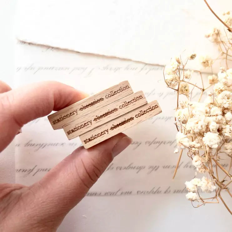 Hand holding the Stationery Obsession Rubber Stamp wooden blocks with flowers on white
