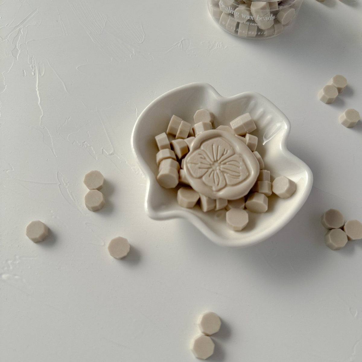 Round wax seals made with Steamed Milk Wax Beads arranged in a white ceramic dish, top-down view on grey