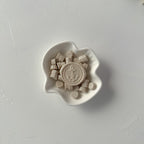 Small white dish with decorative elements on a light gray background