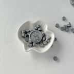 Heart-shaped white dish with gray hexagonal stones on a light gray background