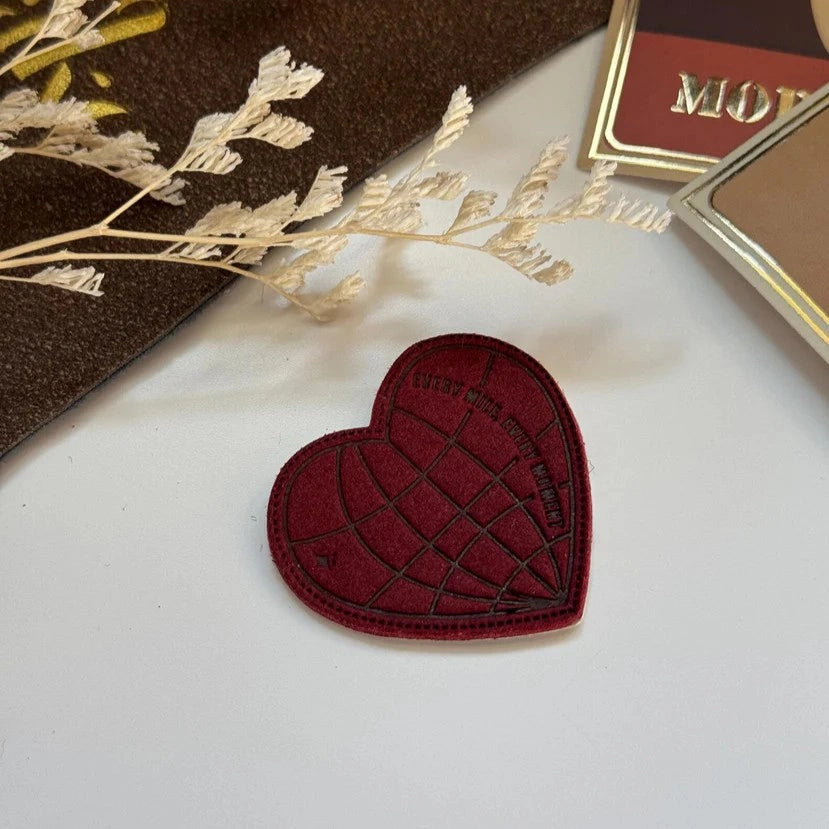 Red heart-shaped object on a white surface with decorative elements