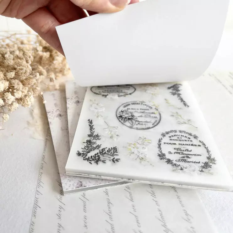 The Vintage One Sticker Book text and floral sticker pages stacked on a marble surface