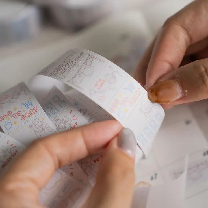 Hands peeling a strip of Daily Life Label Sticker Tape with small activity illustrations