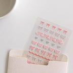 Sheet of decorative stickers with bows and hearts on a white surface
