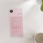 Sheet of decorative stickers with bows and hearts on a pink background, placed on a white surface.