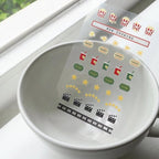 White bowl with clear film stickers featuring movie-themed icons on a white surface.