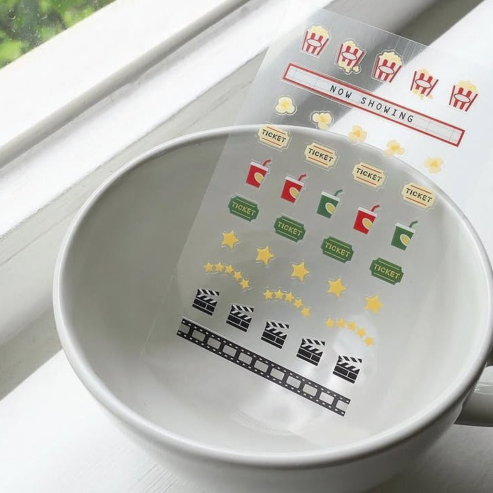 White bowl with clear film stickers showing movie-themed icons, from the Deco 16 Sticker Sheet