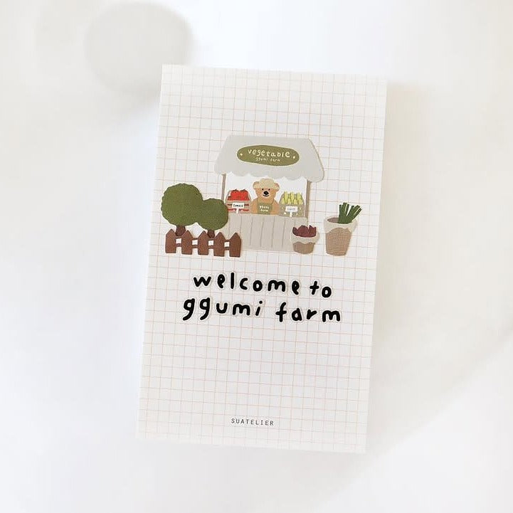 Grid towel with a cartoon bear and 'welcome to ggumi farm' text, from the Ggumi Farm Sticker Sheet