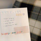 Notebook with 2022 and 'happy new year' text on a tiled floor background
