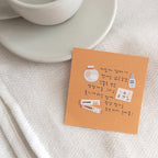 Note with illustrations and text on a textured surface with a cup in the background