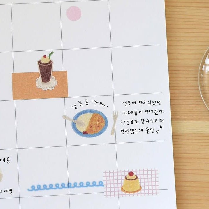 Sheet of paper with food illustrations and text on a wooden surface, from the Kissaten Sticker Sheet