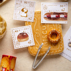 Biscuit-shaped container with decorative stamps and tongs on a textured surface