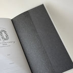 Open book with a gray cover and white pages on a light background