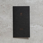 Black notebook with 'SLIM' branding on a textured gray surface