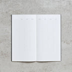 Open notebook with grid paper on a concrete surface