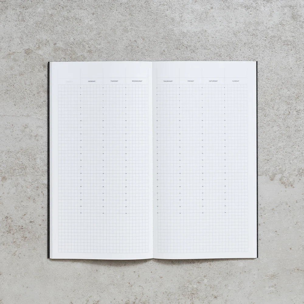 Open Take A Note Slim Weekly Planner showing its grid pages on a concrete surface