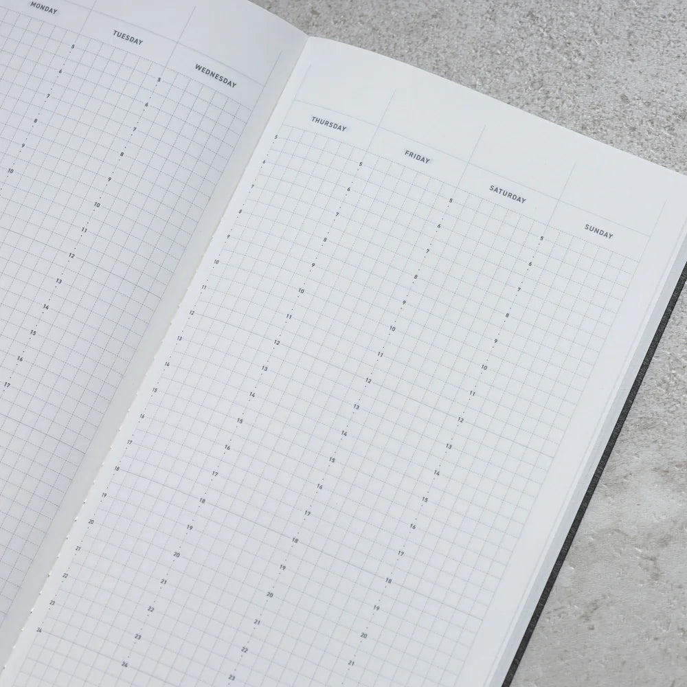 Take A Note Slim Weekly Planner open to its weekly grid layout on a textured surface