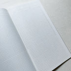 Open notebook with grid paper on a light gray background