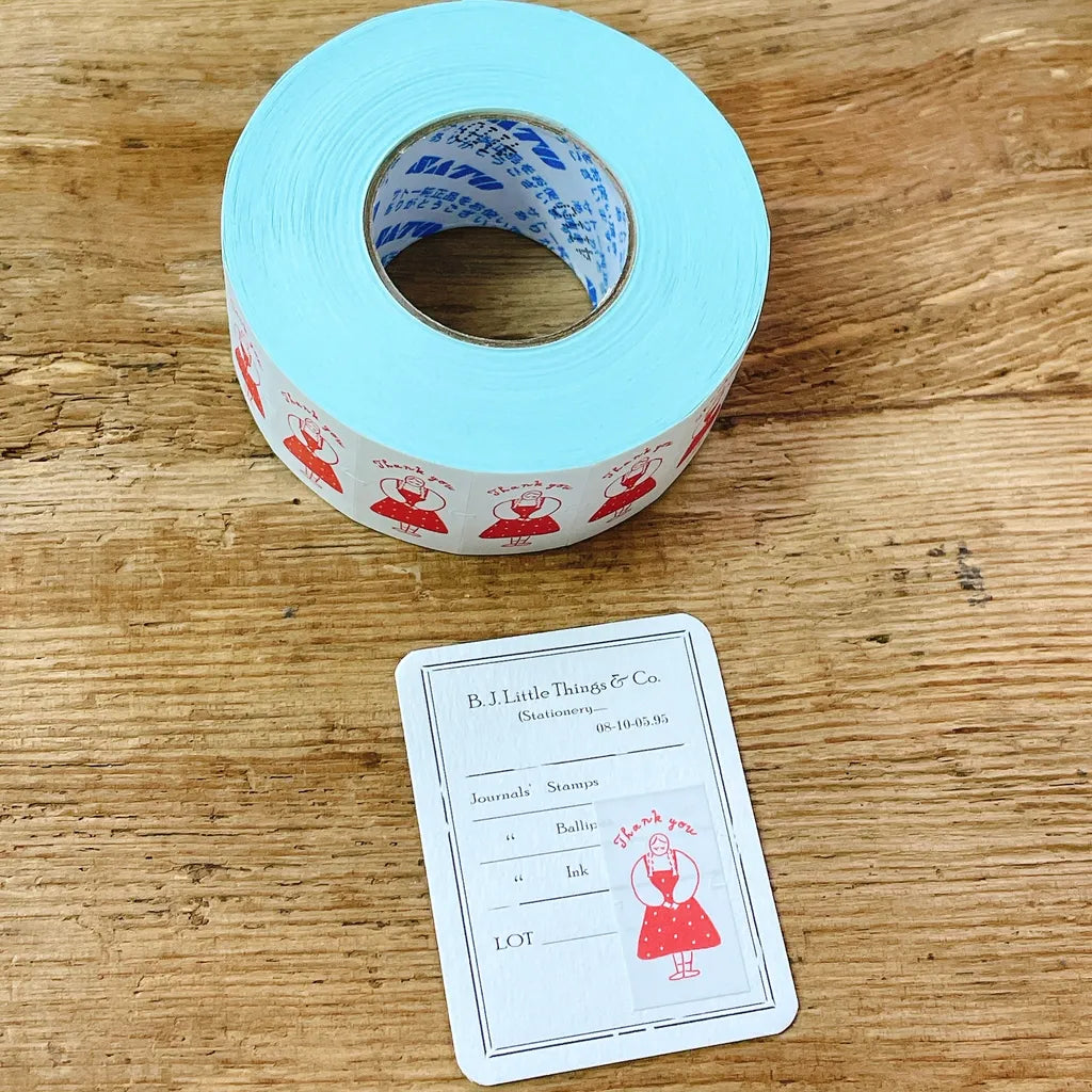 Roll of Thank You Label Sticker Tape by Stamp Marche in blue with red designs on a wooden surface
