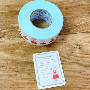 Roll of Thank You Label Sticker Tape by Stamp Marche in blue with red designs on a wooden surface
