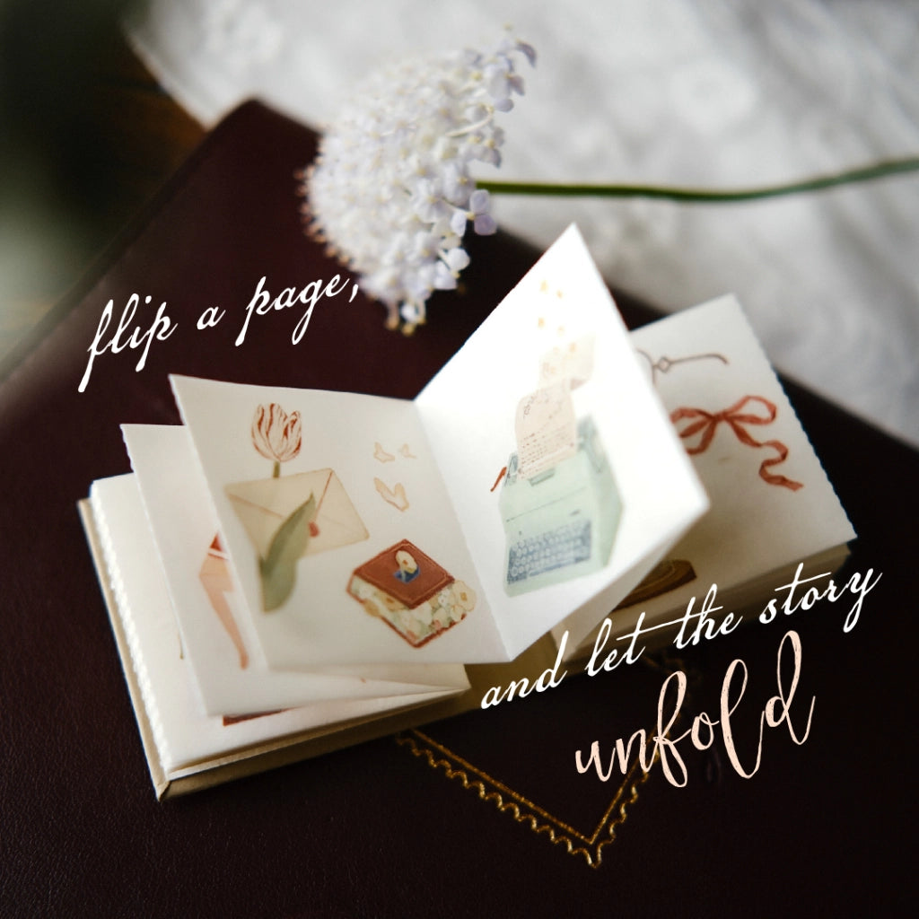 Small book with illustrations of food and flowers, text 'flip a page and let the story unfold', blurred background