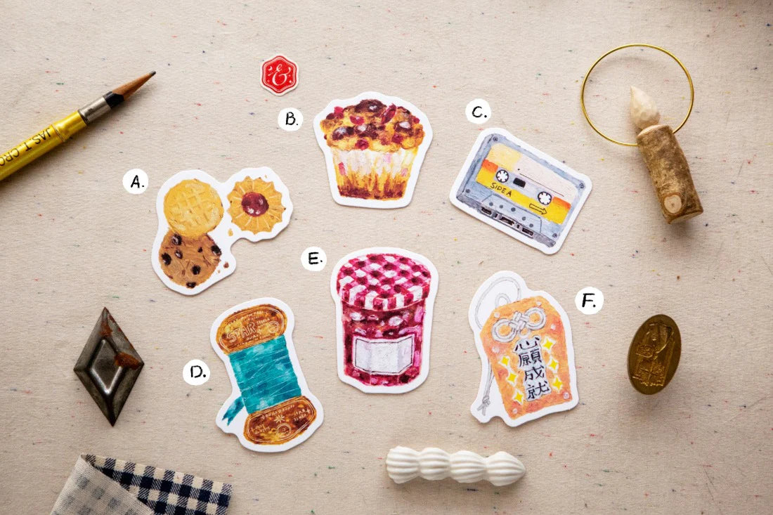 Set of colorful food-themed stickers on a textured surface with a pen and other items.