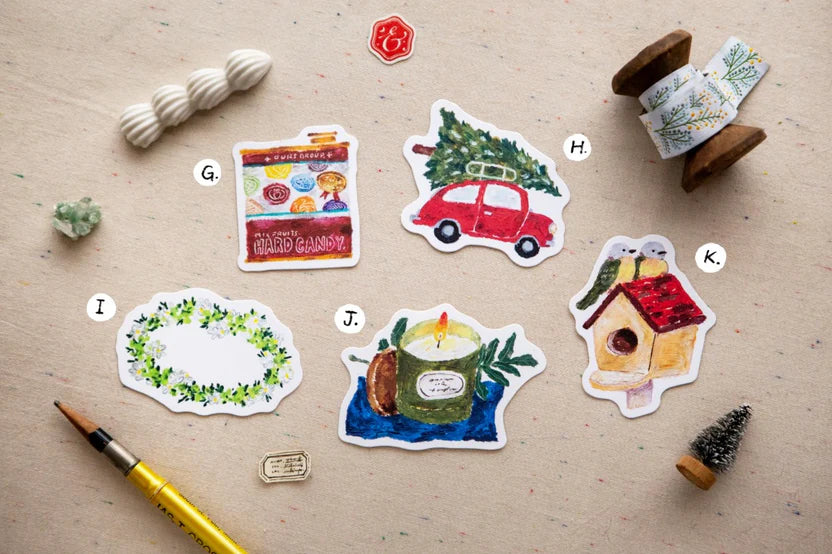 Set of decorative stickers on a textured surface with a paintbrush and spool of thread.