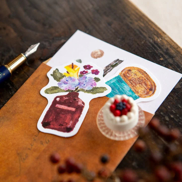 Sticker with floral design on a wooden surface with a fountain pen.