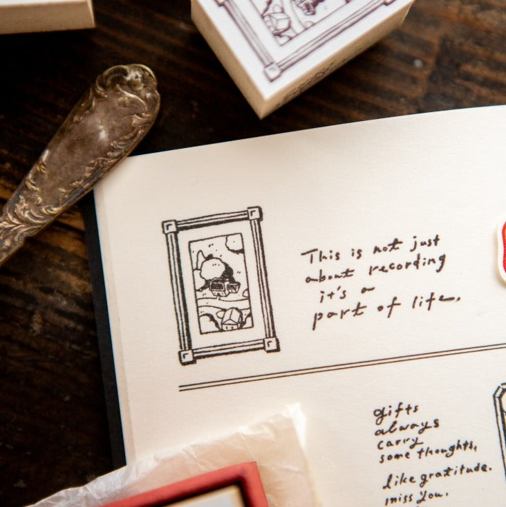 Close-up of a book with text and illustrations, including a rubber stamp and ink pad on a wooden surface.