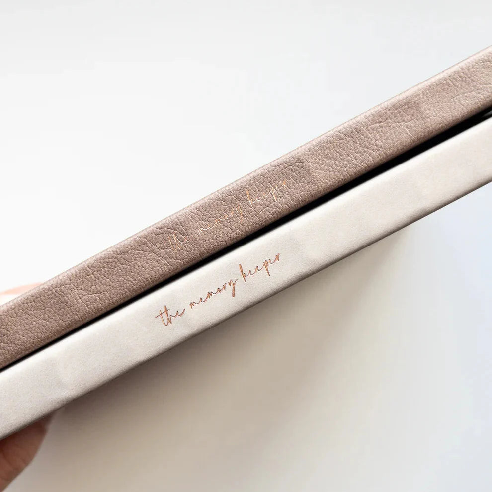 The Memory Keeper A5 Journal spines with gold foil text on neutral textured covers, close-up
