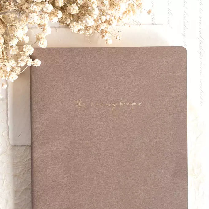 The Memory Keeper A5 Undated Journal in brown with gold title and dried flowers on a light backdrop