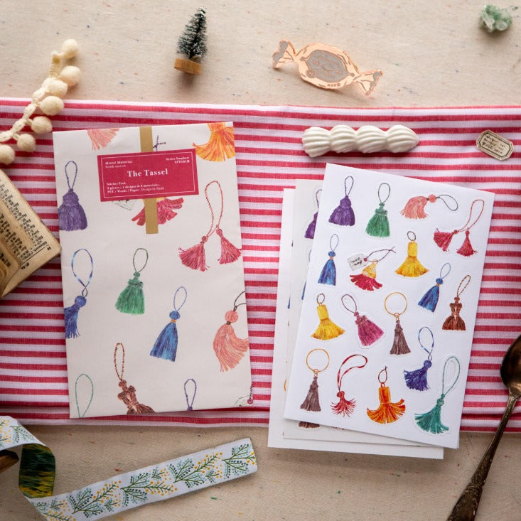 The Tassel Sticker Pack colorful tassel designs on cards over a striped fabric backdrop