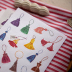 Colorful tassel designs on a card with a red and white striped background