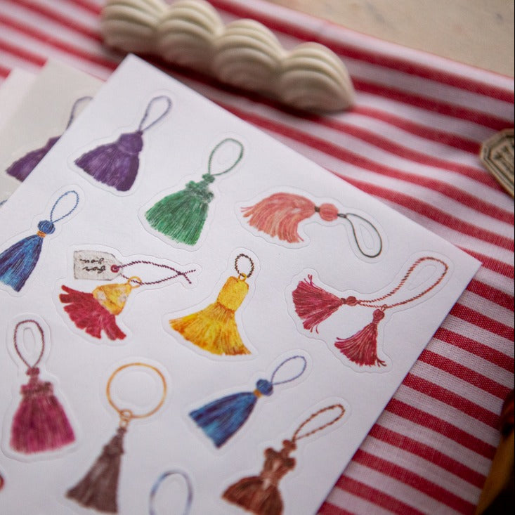 The Tassel Sticker Pack vibrant tassels on a card with a red and white striped backdrop