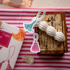 Decorative tassel with vintage-style packaging on a striped fabric background